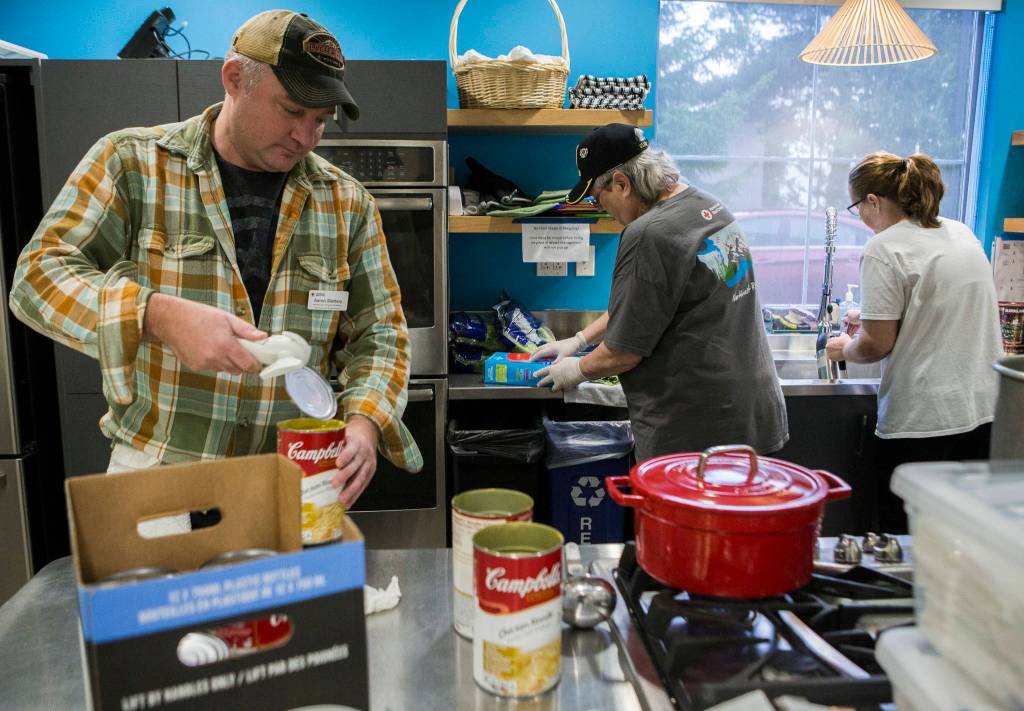 Aaron Slattery (left) opens cans of soup for lunch as volunteers prep food during the Heros Cafe at the Verdant Community Wellness Center on Nov. 26. (Olivia Vanni / The Herald)