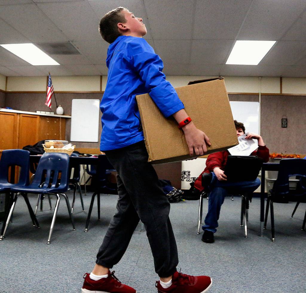 Evan Dault carries a heavy load in his Social Skills classroom at North Lake Middle School. His class is helping boost supplies at the Lake Stevens Community Food Bank, and on Wednesday the kids sorted and boxed up the groceries. (Dan Bates / The Herald)