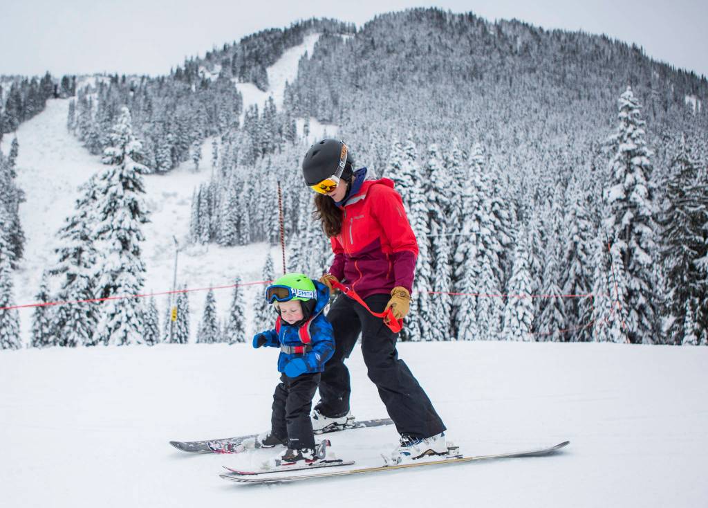 Tenet Meish helps her son, Rio, 2, ski down the slope on opening day at Stevens Pass on Wednesday. (Olivia Vanni / The Herald)