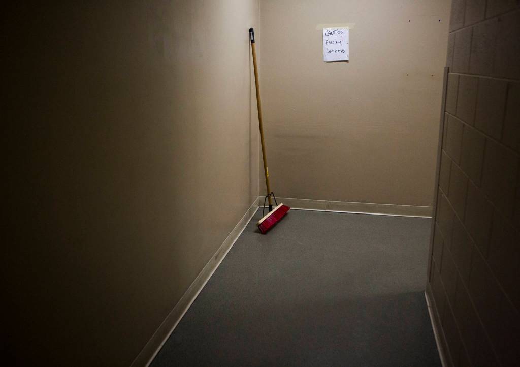 A broom leans agains a wall with a CAUTION FALLING LOCKERS sign at the Everett Family Branch YMCA on Wednesday in Everett. (Olivia Vanni / The Herald)