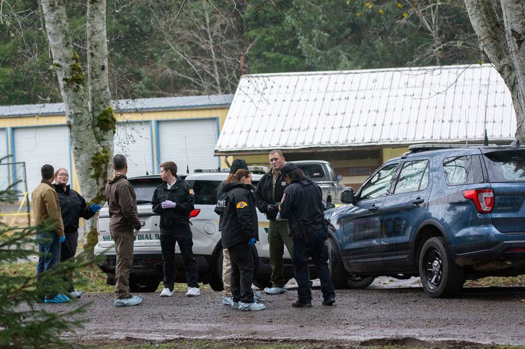 Investigators talk before walking through the scene where 19-year-old Tristen Pisani was shot and killed in Forks on Sunday. (Jesse Major/Peninsula Daily News)