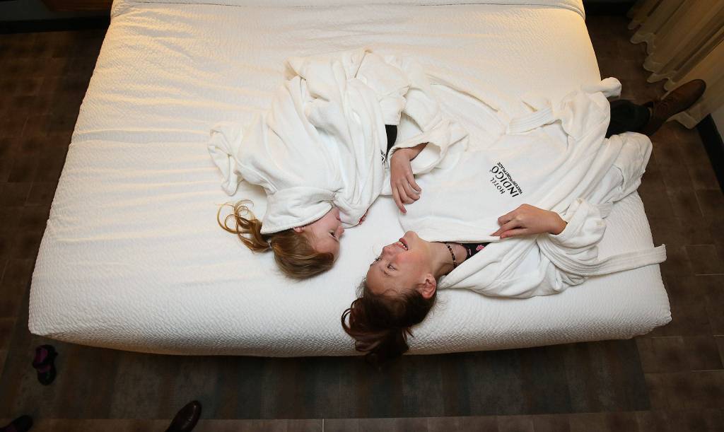 Sisters Alice (left) and Lily Heilman try on bathrobes and lie on a bed in one of the rooms at the Hotel Indigo Everett during its grand opening party Wednesday. (Andy Bronson / The Herald)