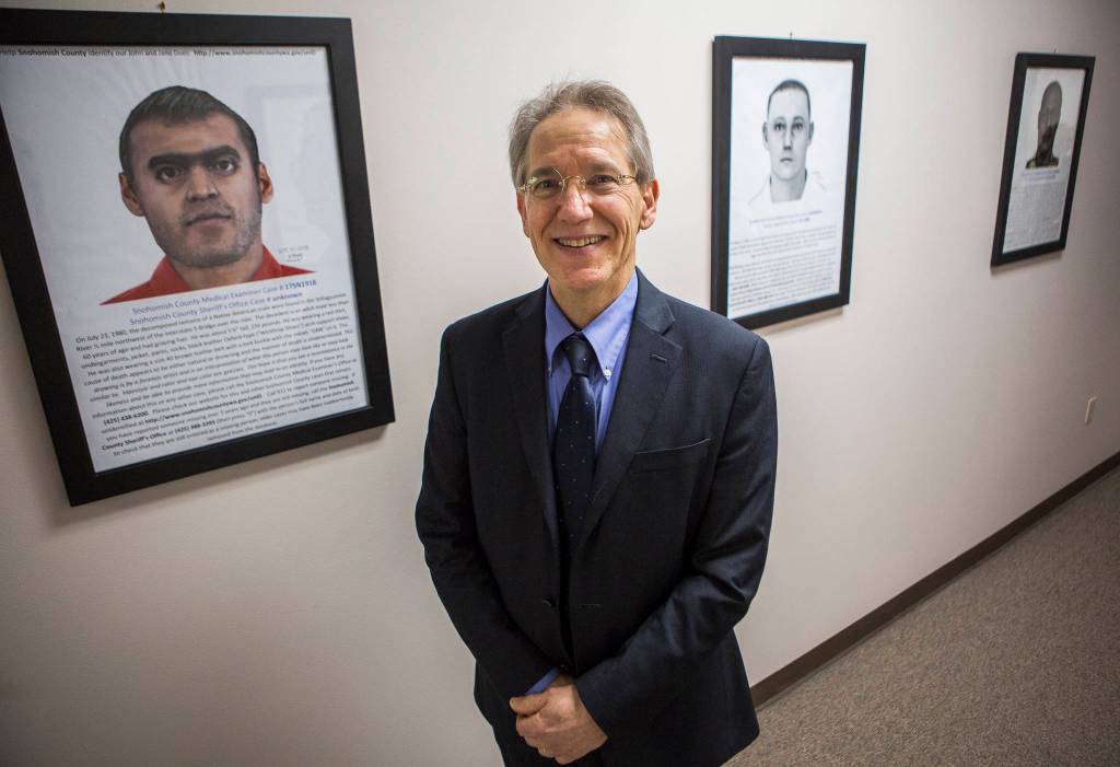 Dr. Daniel Selove pictured with three cold cases at the Snohomish County Medical Examiners Office on Dec. 4 in Everett. (Olivia Vanni / The Herald)