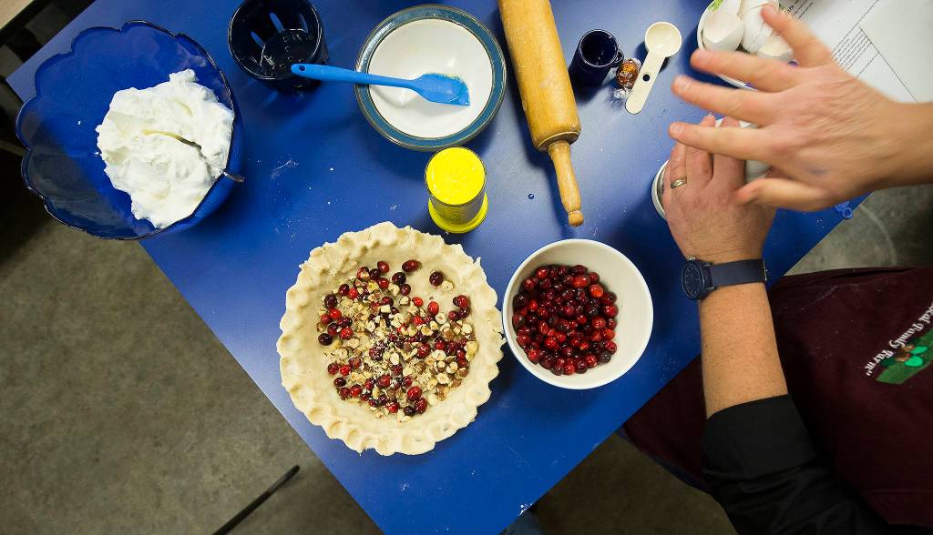 Karen Fuentes chops hazelnuts to add to a cranberry pie during a cooking demonstration at her farm near Silvana. (Andy Bronson / The Herald)