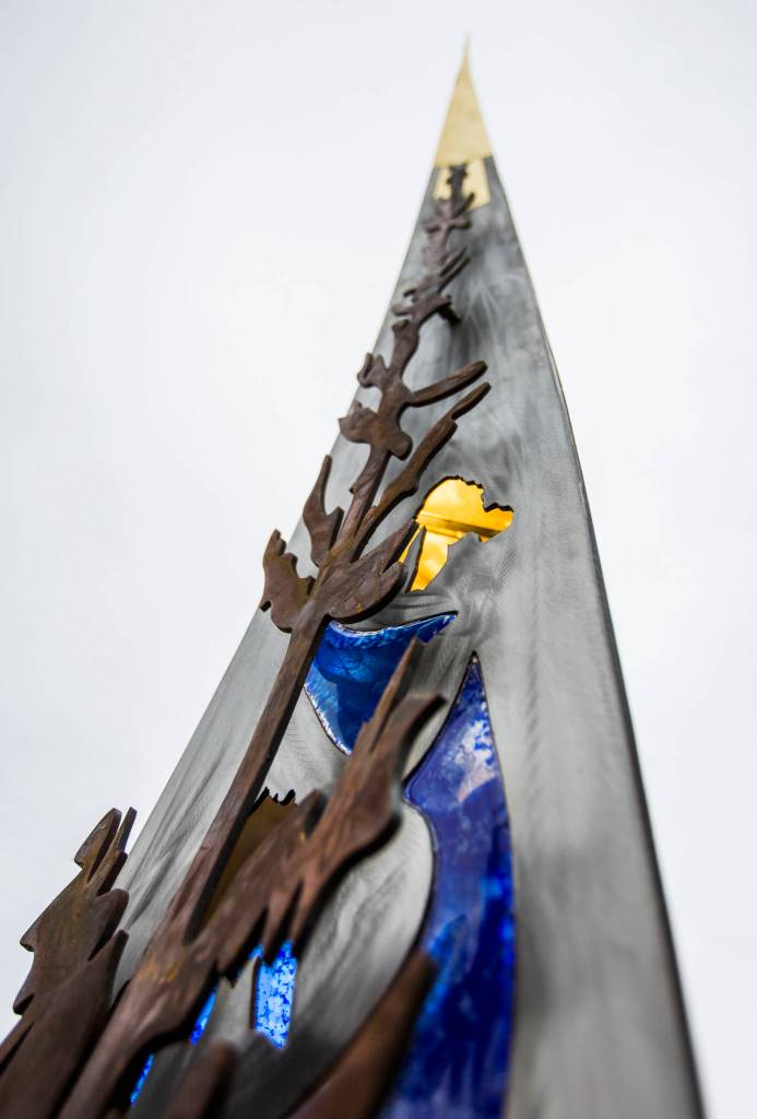 Monroes new sculpture features an outline of jagged mountain peaks, river rocks and blue glass (to represent the Snohomish and Skykomish rivers flowing nearby) and an alpine tree on its front. (Olivia Vanni / The Herald)