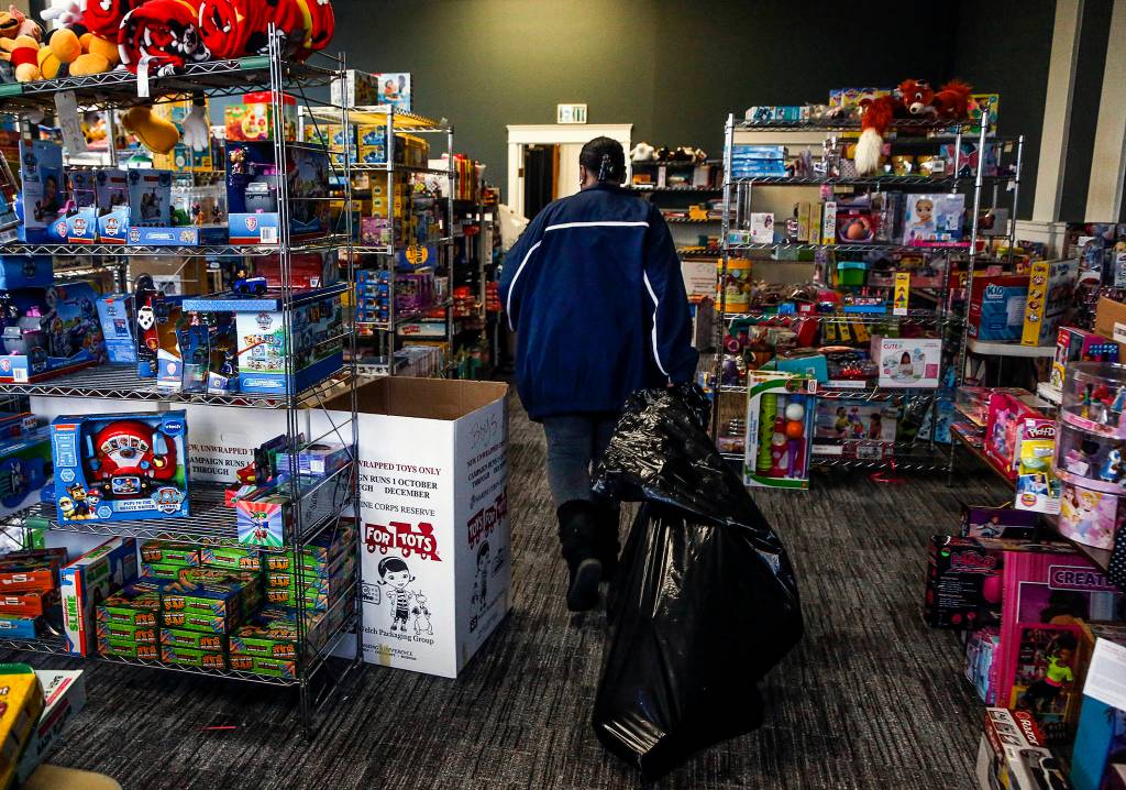 Dan Bates / The Herald                                Having found what she was looking for, Mary Butler heads out of the Toys for Tots distribution room at Everetts Foundation Church, dragging a large bag behind her.