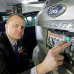 Tim Eyman, a career anti-tax initiative promoter, poses for a photo with the expired car registration tabs on his SUV on Nov. 26 in a parking garage in Seattle. (AP Photo/Ted S. Warren)