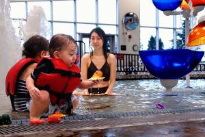 Odin Frye, 2, plays near his sister Emma, 4, and his mom, Saeko Frye, in the recreation pool at the new Everett Family YMCA. Odin found a colorful octopus in the shallows of the childrens pool, which has a zero-entry beach. (Dan Bates / The Herald)