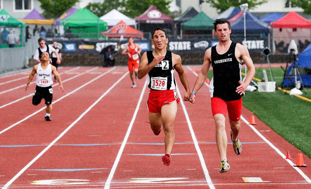 Snohomishs Humoody Smith (1528) and guide Zebedee Kumley cross the finish line first in the 200 Meter Ambulatory Dash at the Washington State track finals at Mount Tahoma Stadium on May 25, 2019, in Tacoma. (Andy Bronson / The Herald)