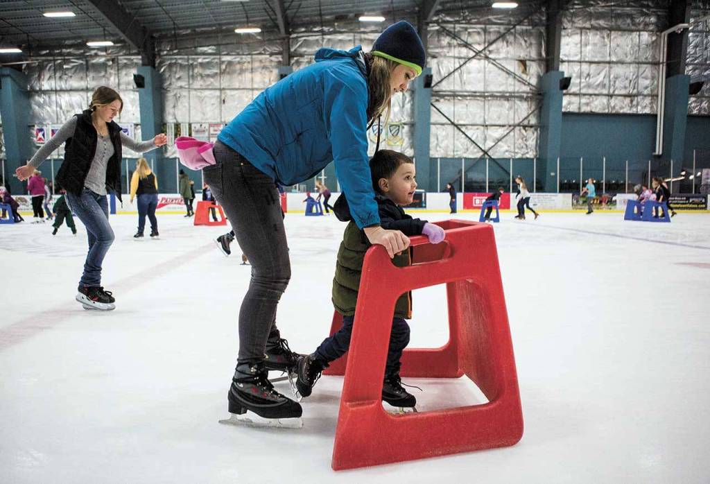 Kellie Alleman helps her son Camden Alleman as he learns to skate with a walker at the Everett Community Ice Rink. (Olivia Vanni / Herald file)