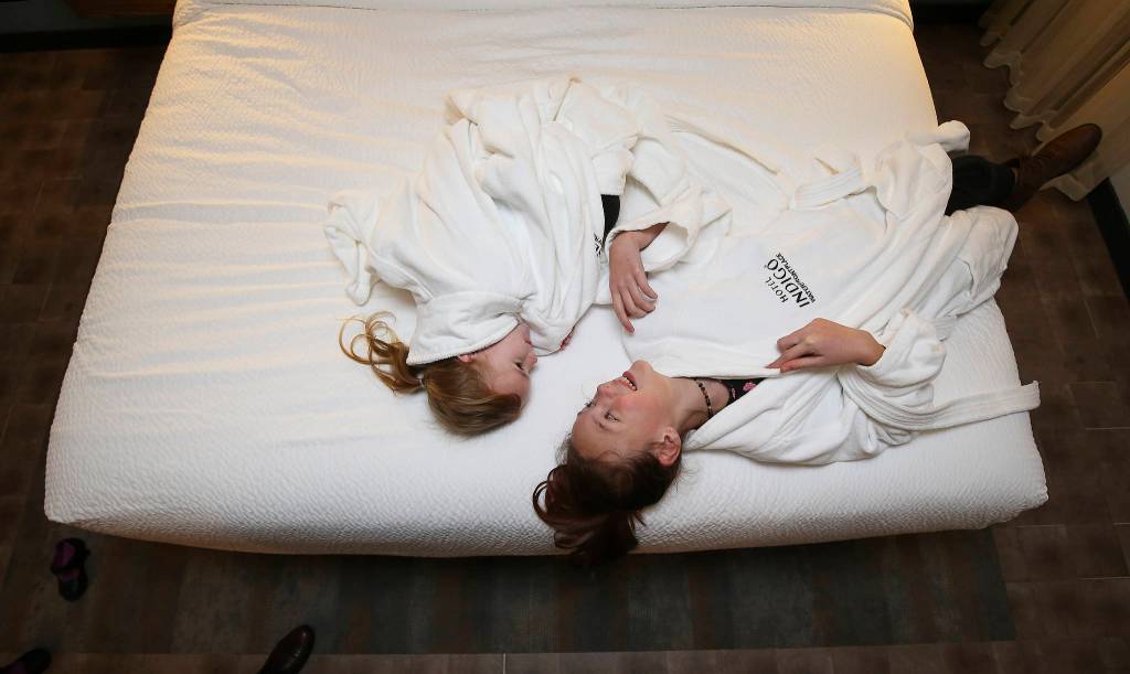 Sisters Alice and Lily Hellman (right) try on bathrobes and lay on a bed at the Hotel Indigo Everett during its Grand Opening party on Dec. 4 in Everett. (Andy Bronson / The Herald)