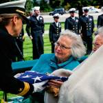 Rear Adm. Linnea Sommer-Weddington, who is with the U.S. Strategic Command in Nebraska, presents a folded American flag to Judy Price and her sister Lana Williams (right). Their mother was the sister of Daniel Guisinger, an Everett sailor who died at Pearl Harbor. (Dan Bates / The Herald)