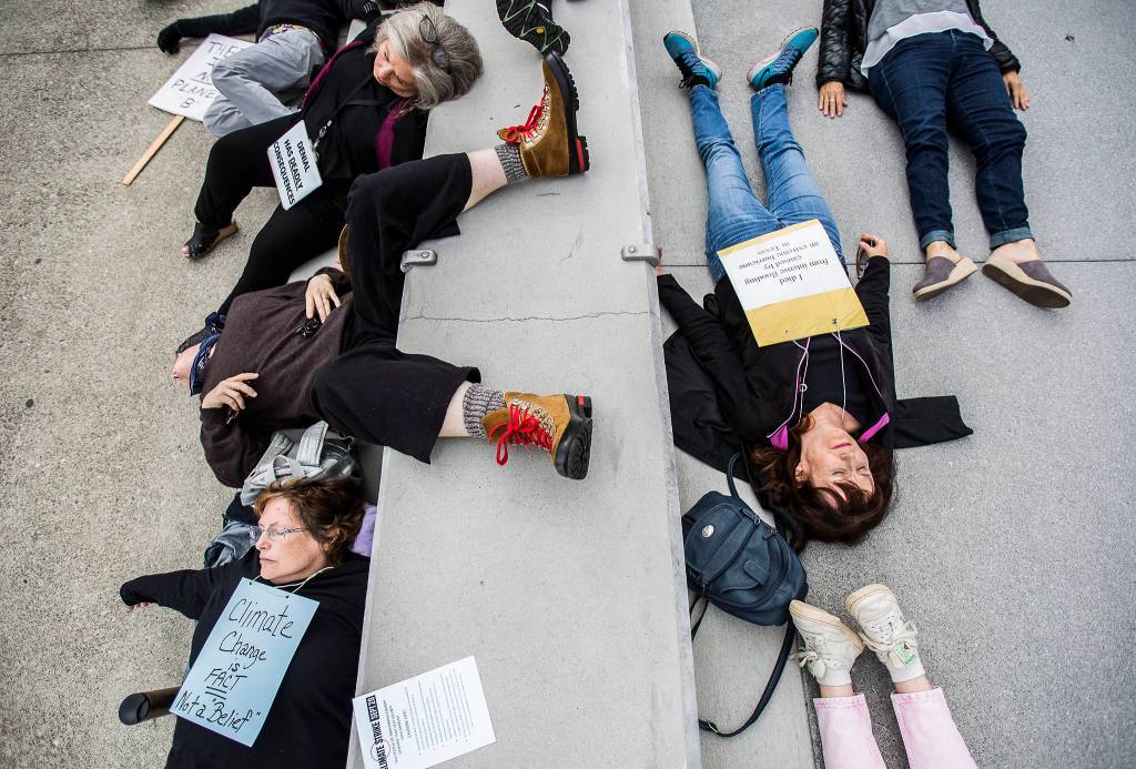 Protestors lie across the ground during the Die-In at the Global Climate Strike at the Snohomish County Campus Plaza on Sept. 20 in Everett. (Olivia Vanni / The Herald)