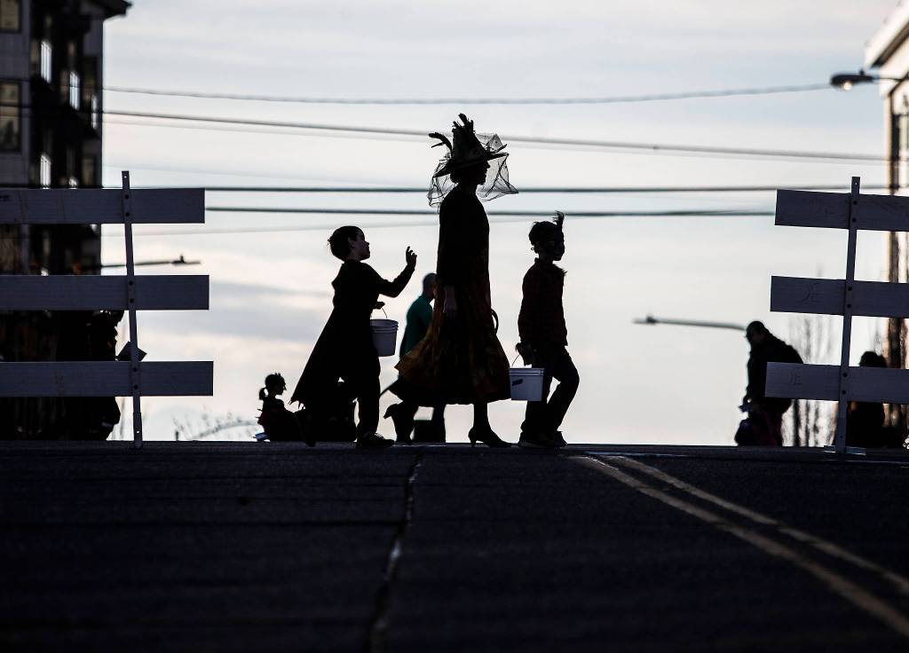 A family in werewolf, witch and vampire costumes crosses California Street during downtown trick-or-treating on Oct. 31 in Everett. (Olivia Vanni / The Herald)