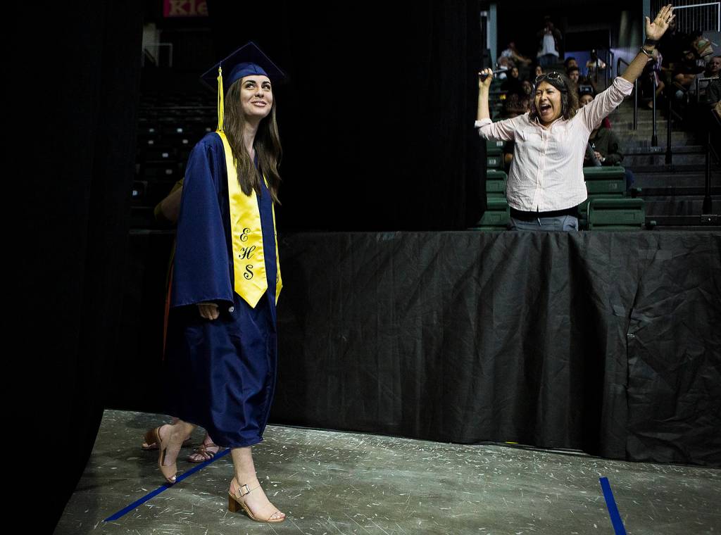 An Everett High School graduate passes by her mother, who cheers when her daughters name is called, during graduation at Angel of the Winds Arena on June 15. (Olivia Vanni / The Herald)