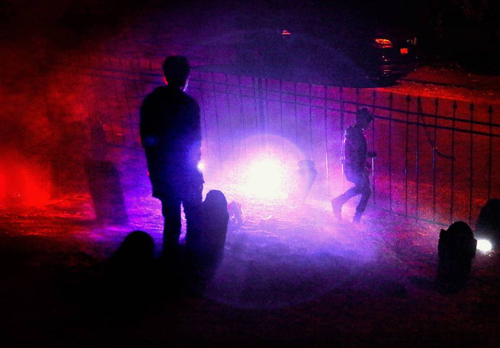 Daxton Ackert, 14, and his 11-year-old brother Kruz check out the special Halloween lighting near the graveyard fence outside their home in Everetts South Forest Park neighborhood. (Dan Bates / The Herald)