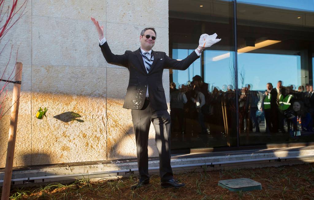 After breaking a champagne bottle after many tries, Brett Smith, Propeller Airports Chief Executive Officer, throws up his hands and the broken bottle during opening day ceremonies of the Paine Field Terminal on March 4. (Andy Bronson / The Herald) F