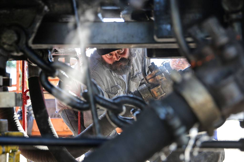 Jake Turner reviews some of the finishing touches on a restored 1947 steam engine at The Newell Corporation in Arlington on June 11. (Kevin Clark / The Herald)