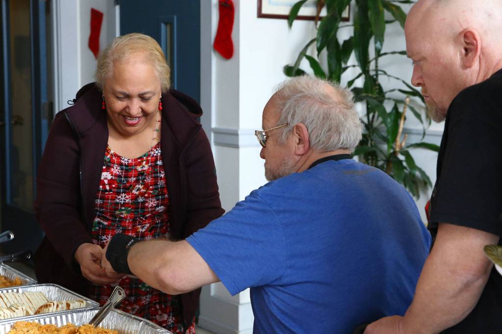 Sue Tugi, family support manager, helps residents of Housing Hope in Everett serve food on Tuesday. (Kevin Clark / The Herald)