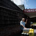 Doug Turner chats with his beer delivery man outside of his grocery store on July 12 in Lake Stevens. (Olivia Vanni / The Herald)