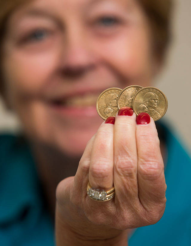 Snohomish County Auditor Carolyn Weikel holds up three of fives coins given to her by her predecessor, for use in deciding election ties. The missing coins were given to the losing candidate after the coin toss to decide the winner. (Andy Bronson / The Herald)