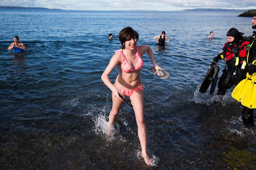 Florida resident Zoe Merrow quickly exits the water as divers in drysuits head into Puget Sound during the annual Polar Bear Plunge at Bracketts Landing on Wednesday in Edmonds. (Andy Bronson / The Herald)