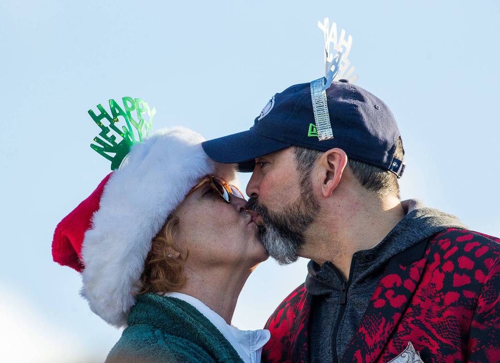 Suzanne Smith and John Jainga kiss after taking part in the annual Polar Bear Plunge at Bracketts Landing on Wednesday in Edmonds. (Andy Bronson / The Herald)