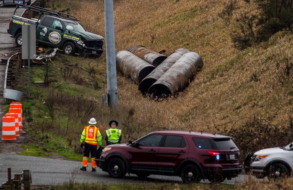 A truck sits in a ditch off of the northbound I-5 lanes, where it went through a barricade next to where a semi flipped on Thursday in Lynnwood. (Olivia Vanni / The Herald).
