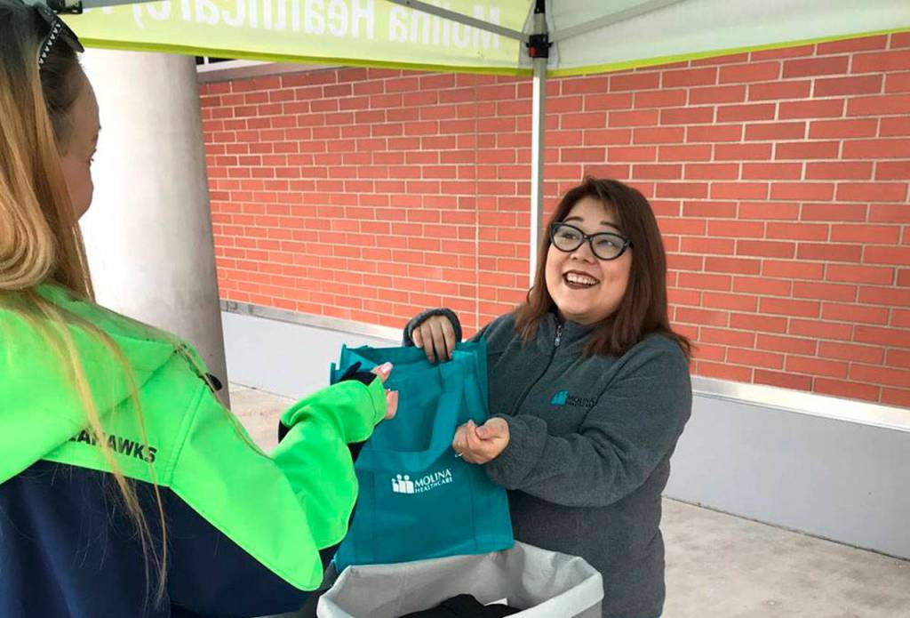 A Molina Healthcare of Washington community engagement specialist gives someone a reusable tote bag with a beanie and a pair of gloves and socks on Tuesday at Community Health Center of Snohomish County in north Everett. (Molina Healthcare of Washington)
