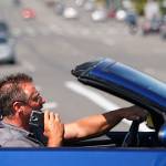 The driver of a BMW convertible appears to be talking on a cell phone while driving through the 41st Street and Colby Avenue intersection July 22, 2015. Doing so is illegal and dangerous, but is becoming less common. (Dan Bates / Herald file)