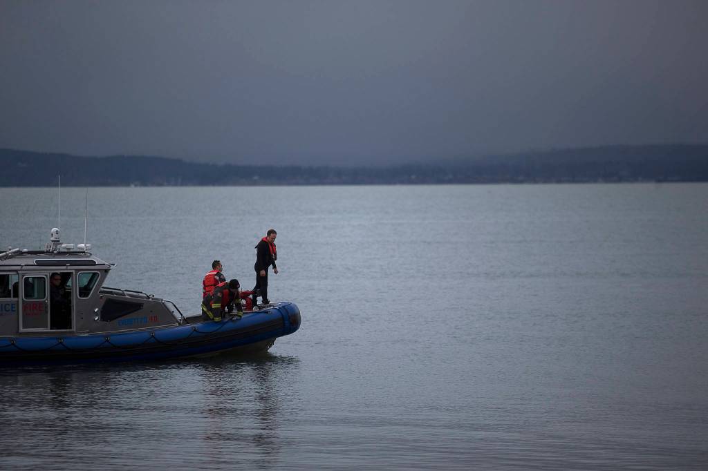 Everett rescue personnel peer over the sides of a boat in search of a man who was last seen swimming to shore after his inflatable boat capsized off the beach north of the Mukilteo ferry Wednesday. (Andy Bronson / The Herald)