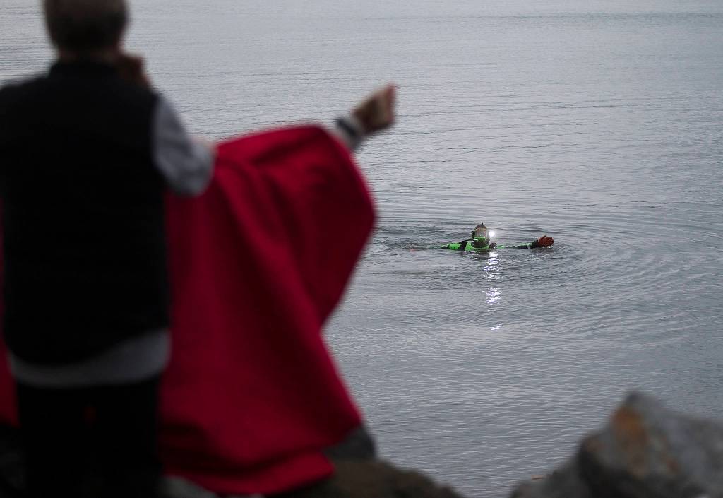 A Snohomish County Sheriffs Office diver uses hand signals to ask an eyewitness to help him during the search for a man who was last seen swimming to shore after his inflatable boat capsized off the beach north of the Mukilteo ferry Wednesday. (Andy Bronson / The Herald)