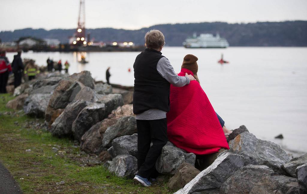 A witness is comforted as rescue personnel search for a man who was last seen swimming to shore after his inflatable boat capsized off the beach north of the Mukilteo ferry Wednesday. (Andy Bronson / The Herald)