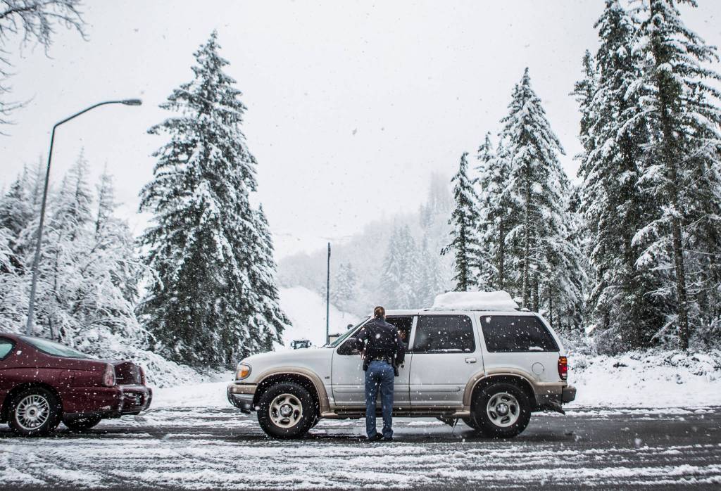 Washington State Patrol Trooper Heather Axtman talks to local residents hoping to get an escort into Index on Monday because U.S. 2 was closed to traffic. (Olivia Vanni / The Herald)
