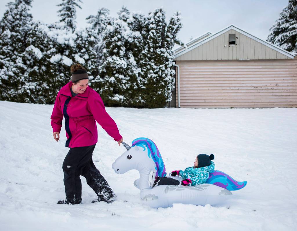 Audrey Boucock, 3, gets pulled up the hill in a makeshift unicorn blowup sled by her mother Laura Boucock on Monday in Everett. (Olivia Vanni / The Herald)