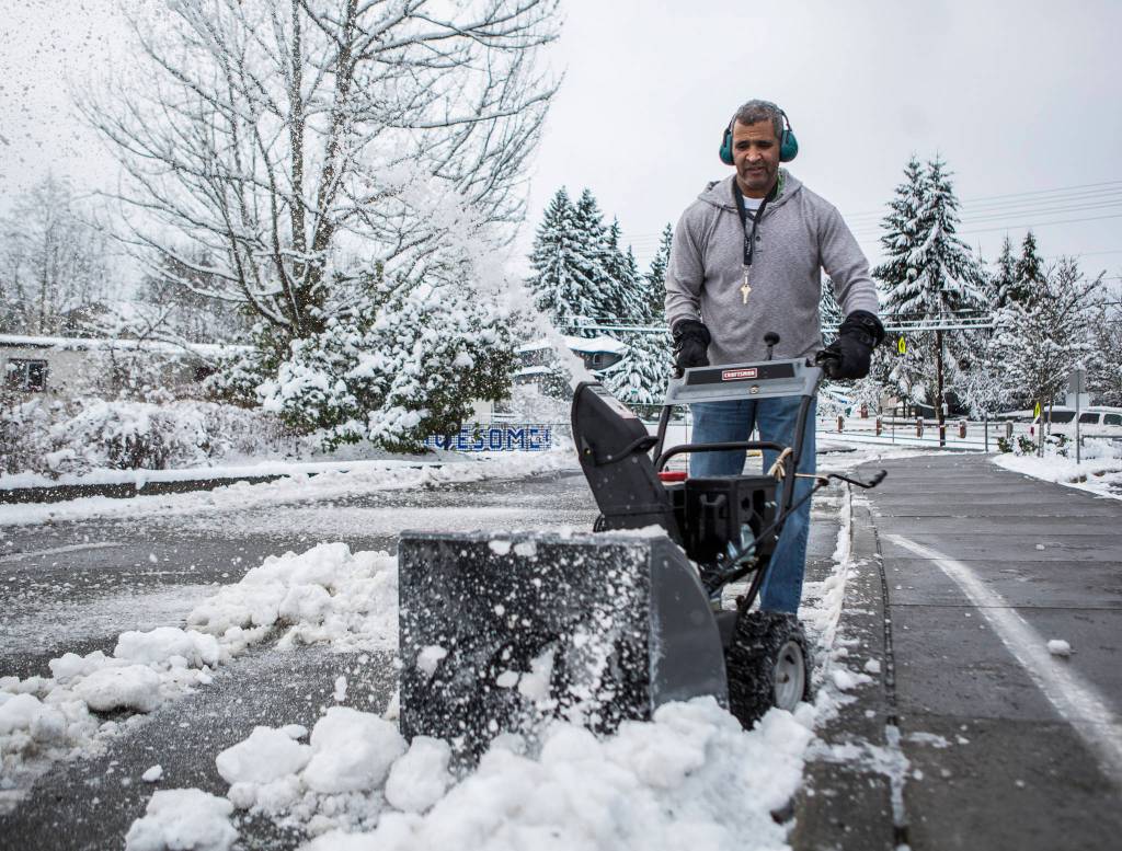 Brian Quantrille blows snow out of the parking lot of Seattle Hill Elementary on Wednesday in Everett. (Olivia Vanni / The Herald)