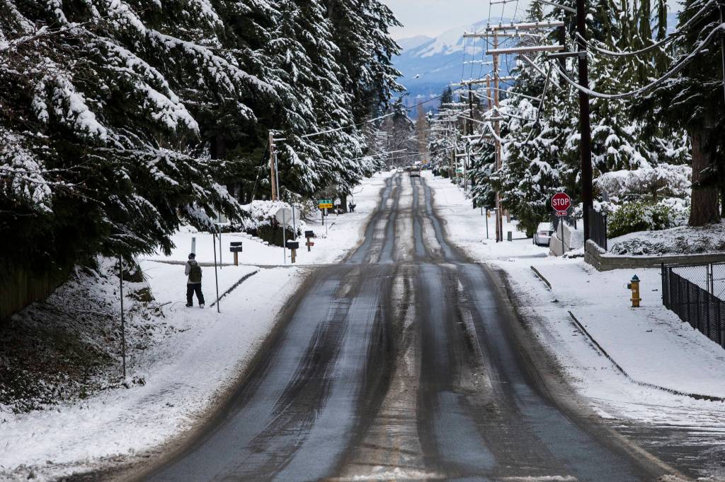 A person walks along a slushy 51st Avenue SE on Wednesday in Everett. (Olivia Vanni / The Herald)