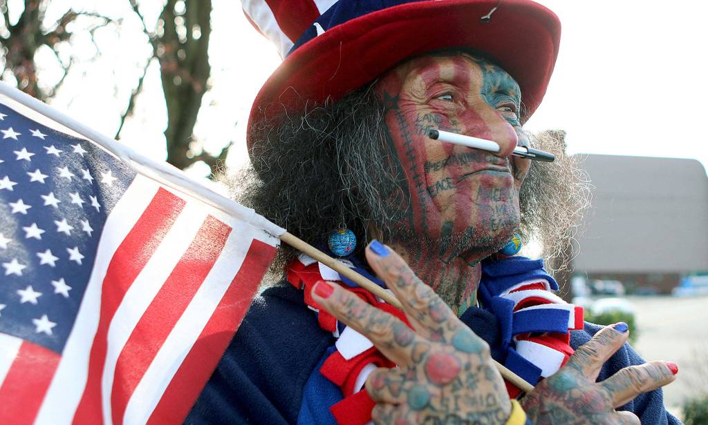 Samiu Bloomfield, seen here in March 2016, stands on Broadway in Everett looking like a feral version of Uncle Sam as he waves to people. He died Sunday at 70 years old. (Kevin Clark / Herald file)