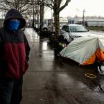 A young man passes time at a spot where people have camped along Smith Avenue north of the Everett Gospel Mission and south of Everett Station, Tuesday. (Dan Bates / The Herald)