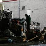 A man secures tarps over personal belongings beneath Interstate 5 overpass next to the Everett Gospel Mission, Tuesday. (Dan Bates / The Herald)