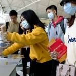 Travelers wearing face masks gather at Hong Kong International Airport on Tuesday to get squirts of antibacterial lotion after the outbreak of a new coronavirus that has reached Snohomish County  the first confirmed case in the U.S. (AP Photo/Ng Han Guan)