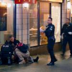 Officers attend to one of several shooting victims outside of McDonalds on Third Avenue on Wednesday in Seattle. The window of the restaurant behind them was shattered after a gunman opened fire in the heavily trafficked downtown area. (David Silver via AP)