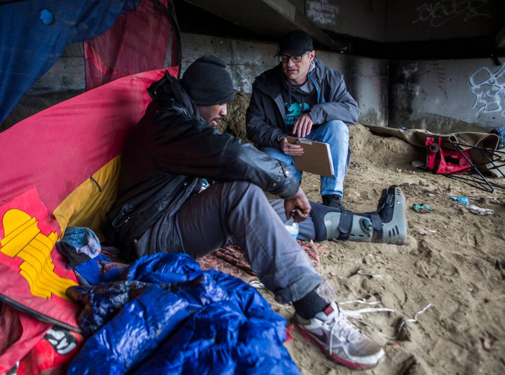 Catholic Community Services navigator Aaron King (right) talks with Kenny Marshall, 39, for the annual Point In Time count on Jan. 23 in Everett. (Olivia Vanni / Herald file)