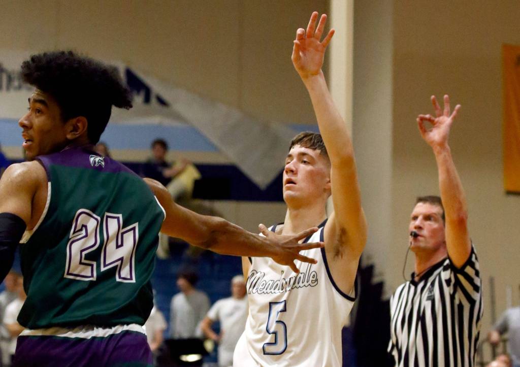 Meadowdales Hunter Moen watches a 3-point shot attempt with Edmonds-Woodways Nikko McNeal Friday evening at Meadowdale High School in Lynnwood January 24, 2019. (Kevin Clark / The Herald)