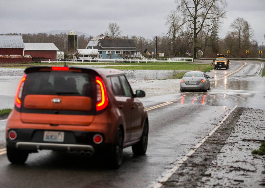 Cars make their way along a flooded road Saturday in Silvana. (Olivia Vanni / The Herald)