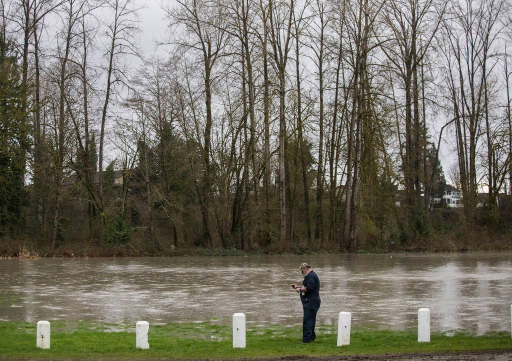 Brian Ramey stops to take a photo of the flooded Twin Rivers County Park on Saturday in Arlington. (Olivia Vanni / The Herald)