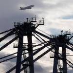 A Boeing Dreamlifter plane flies over the two new cranes Monday at the Port of Everett South Terminalin Everett. At 215-feet tall, the cranes are required to have FAA-approved markings or lighting. (Andy Bronson / The Herald)