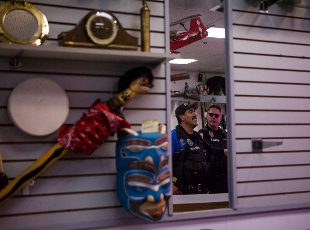 Everett Police Officers Mike Bernardi (left) and Kevin Davis chat with the owner of Sound Loan Pawn Shop, one of the businesses they visited during foot patrol downtown on Thursday. (Olivia Vanni / The Herald)
