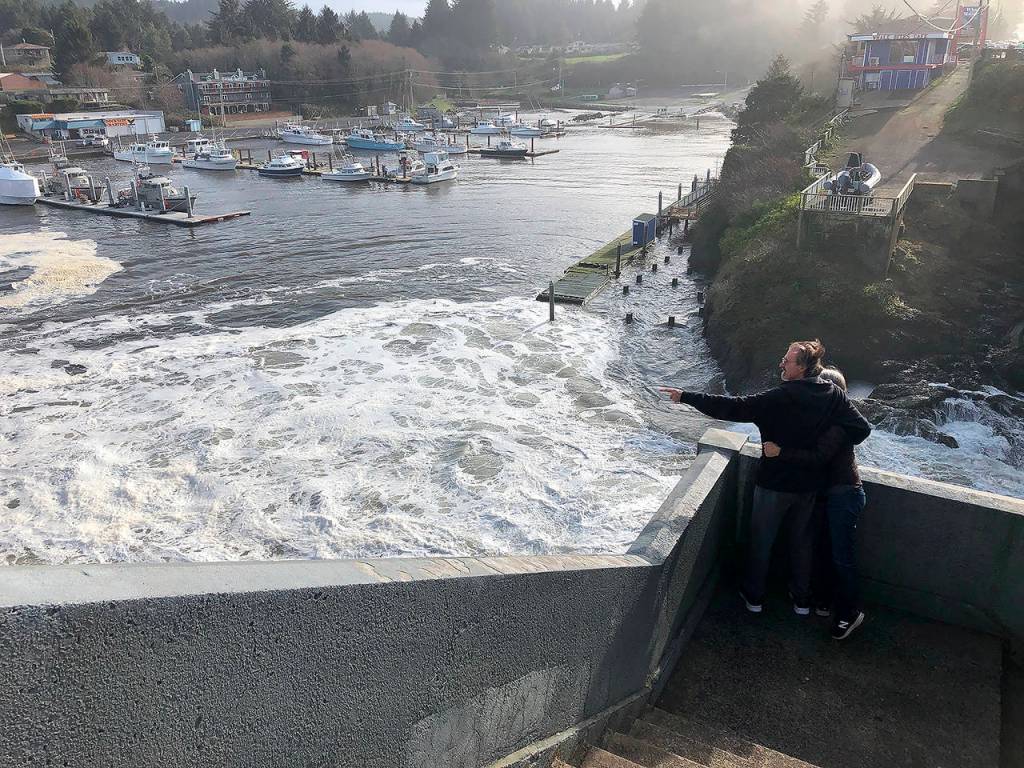 In this Jan. 11 photo, residents watch as an extreme high tide rolls in and floods parts of the harbor in Depoe Bay, Oregon during an extreme high tide that coincided with a big winter storm. (AP Photo/Gillian Flaccus)