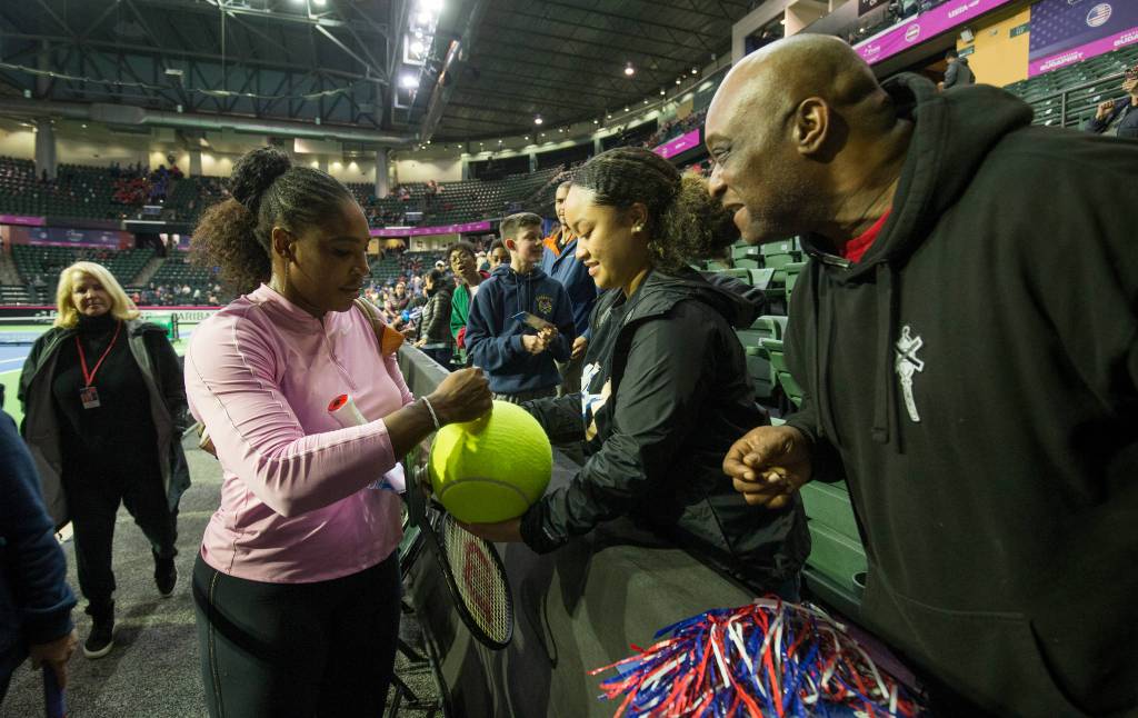 Serena Williams signs a tennis ball for Anissa Blake and her father, Angelo, of Marysville, before the start of the FedCup qualifying rounds at Angel of the Winds Arena on Friday in Everett. (Andy Bronson / The Herald)